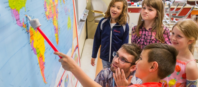 student teaching children, showing them a world map