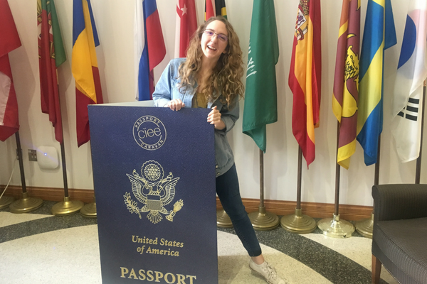 student holding passport poster