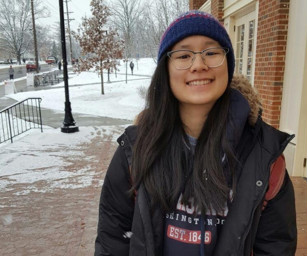 student stands smiling in snowy weather
