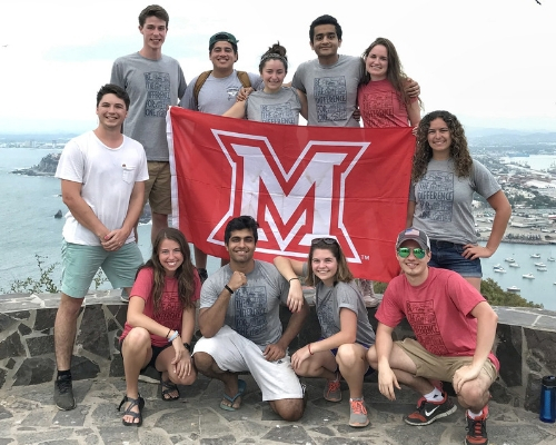 Group photo of Miami students studying abroad in Mexico, holding Miami flag 