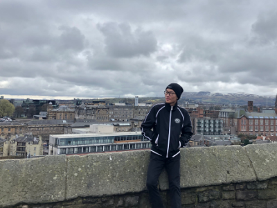 a man standing on a roof, with a city that can be seen behind him