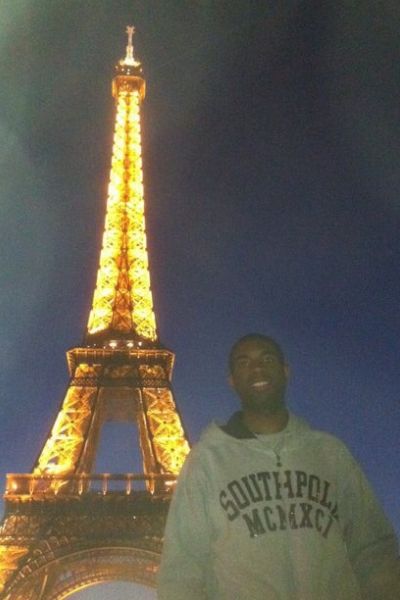 Seth standing in front of the Eiffel Tower, light up at night