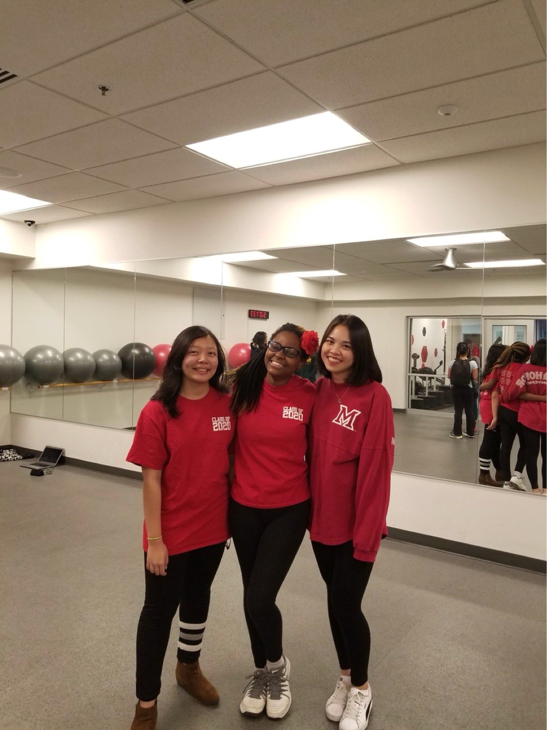 Three friends pose in Miami gear in an exercise class.