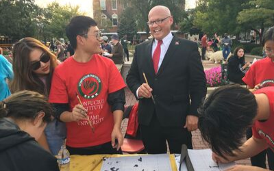 President Crawford smiles while learning calligraphy