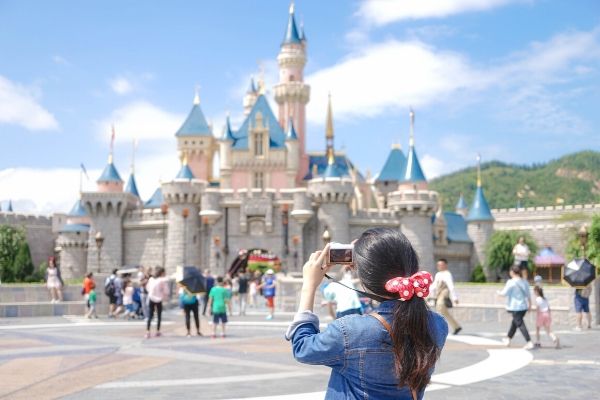 a woman takes a picture of the disney castle