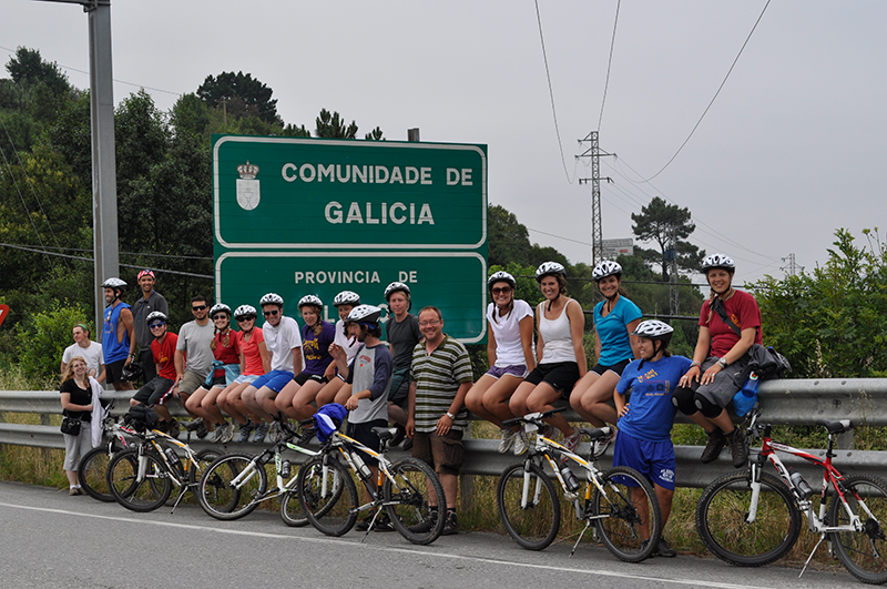 Group of students on bicycles near Galicia road sign