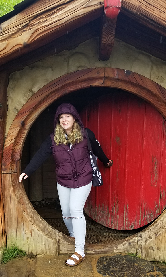 Liz poses in front of a house in Hobbiton