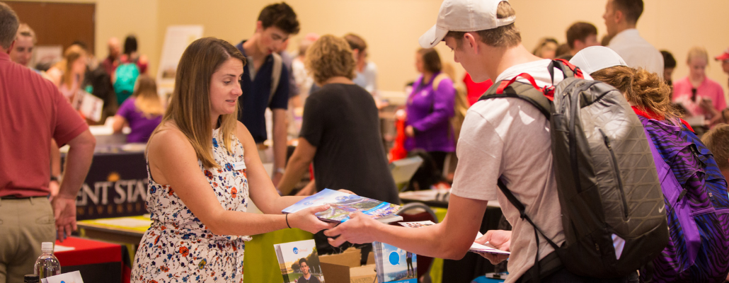 A rep hands out literature to students at a past indoor study abroad fair