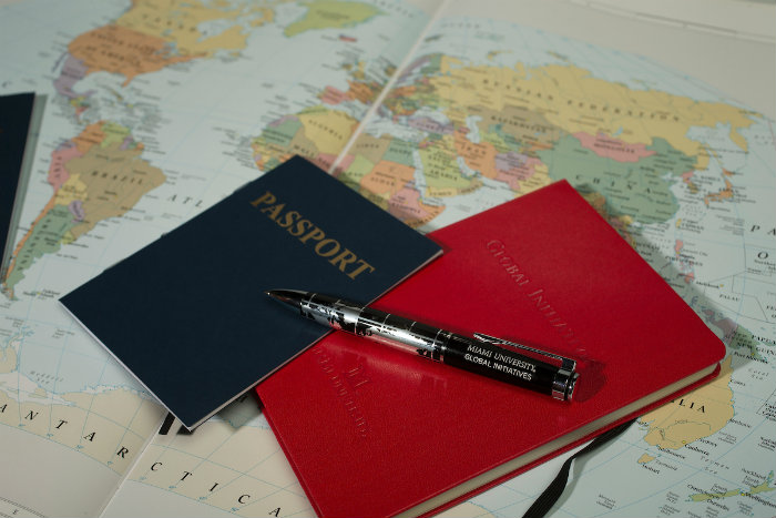 Passport, pen, and notebook on top of a world map