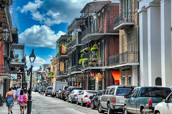 a city street in New Orleans with classic balconies and street lamps visible.png