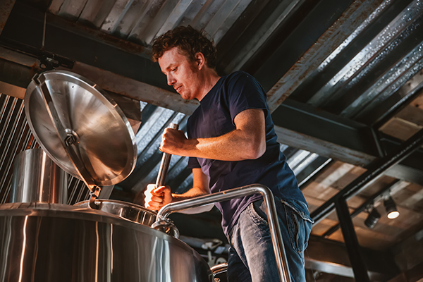 A man tends to a brewing vat