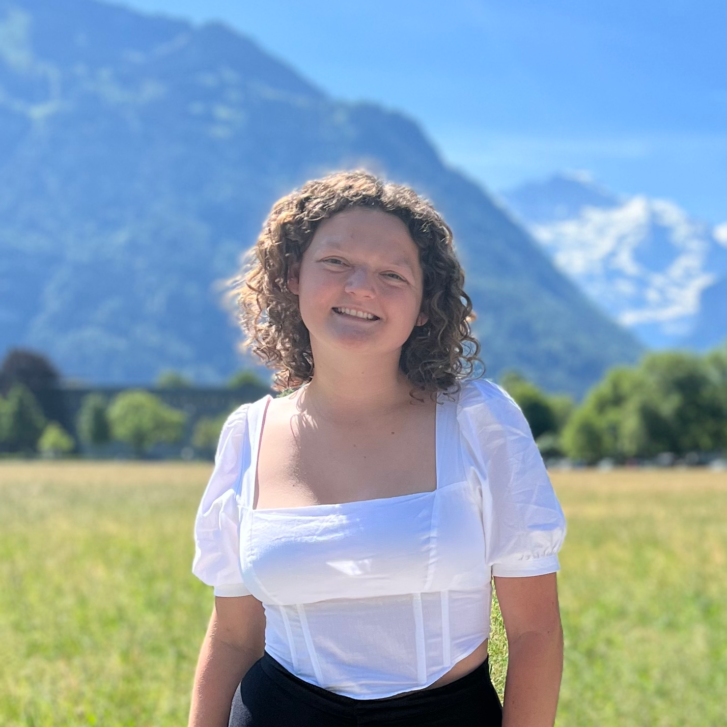 Emily smiles at the camera. Mountains are visible in the background