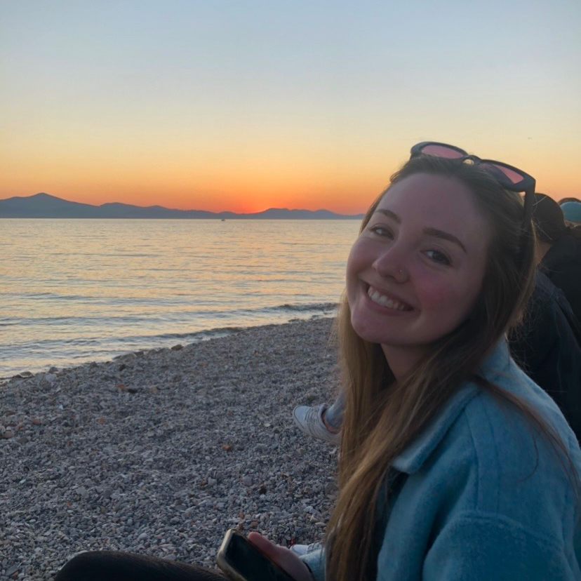 Head tilted, Annaliese poses at sunset in front of a body of water