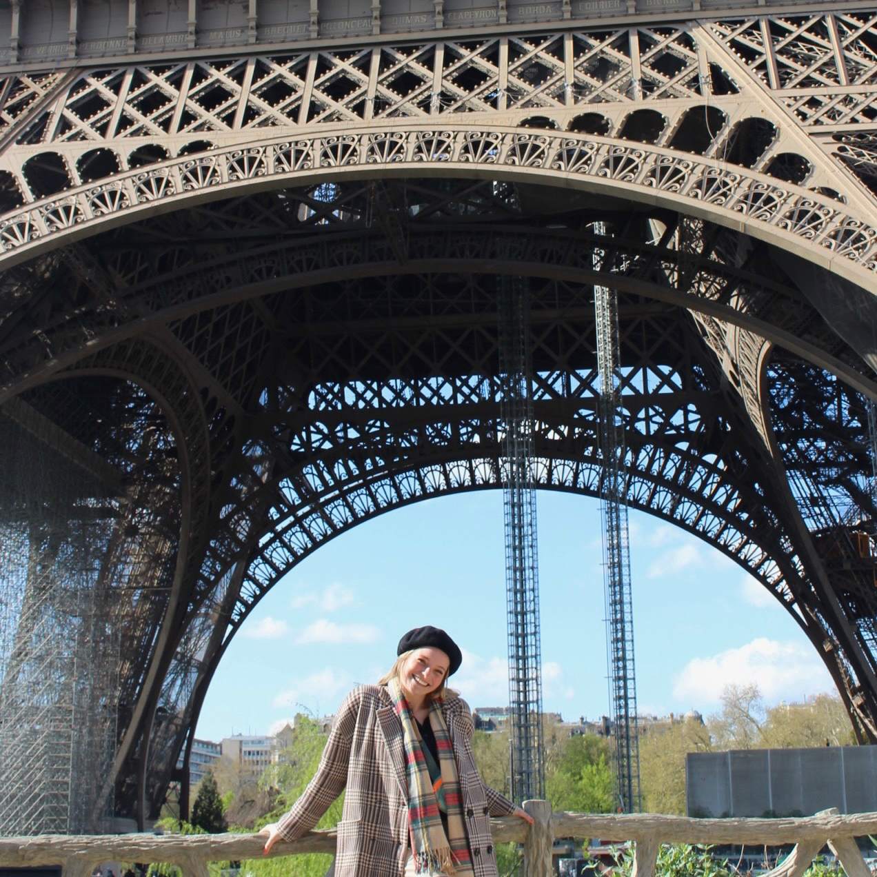 Sophie smiles as she stands beneath the Eiffel Tower