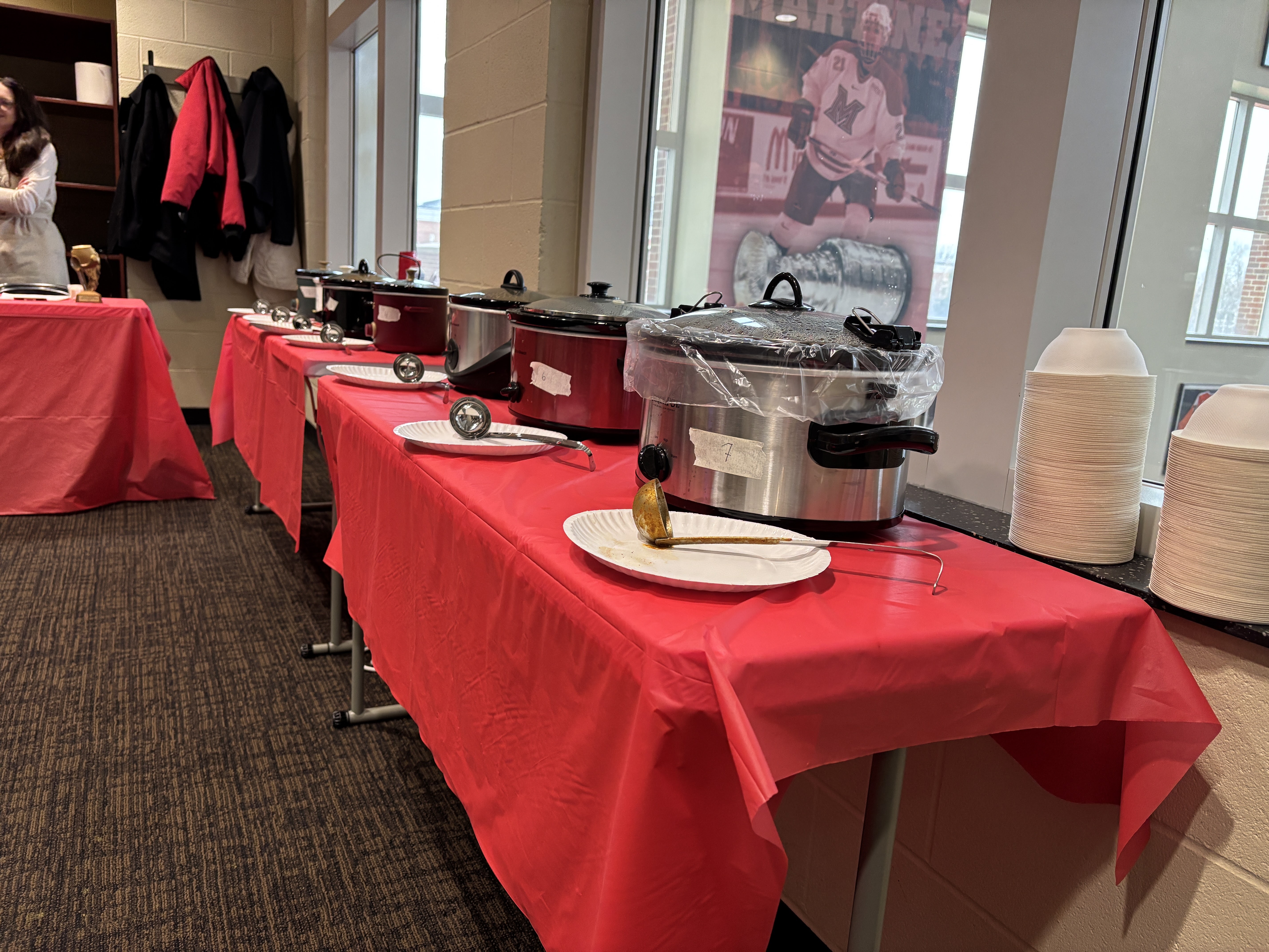 A row of tables with crock pots for chili