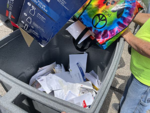 Documents being tossed into a huge garbage can for shredding