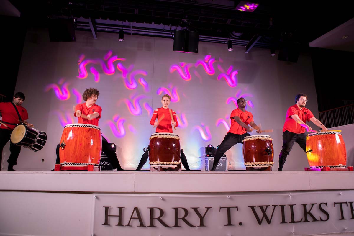 Students on stage playing various drums.
