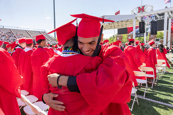 Two Miami University students celebrate during the spring commencement ceremony May 17 at Yager Stadium.