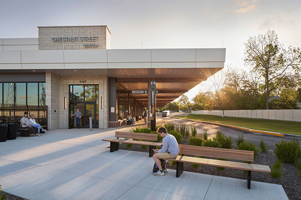 The Chestnut Street multimodal transit hub station entrance with several people sitting on benches on the plaza outside the entrance