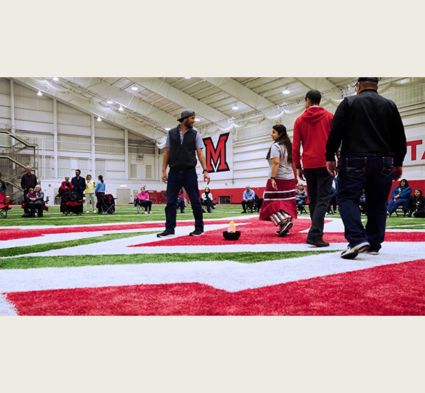 Kara Strass, center right, walks around a flame representing fire with other citizens of the Miami Tribe of Oklahoma during a Tribal dance at the 2024 Myaamiaki Conference at Miami University (photo courtesy of Miami Online.