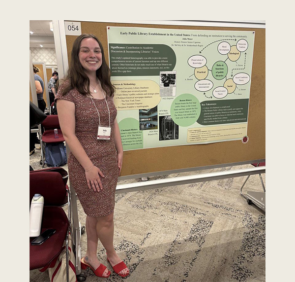 Julia Moser stands next to her undergraduate research poster at the Undergraduate research forum in Shriver Center 