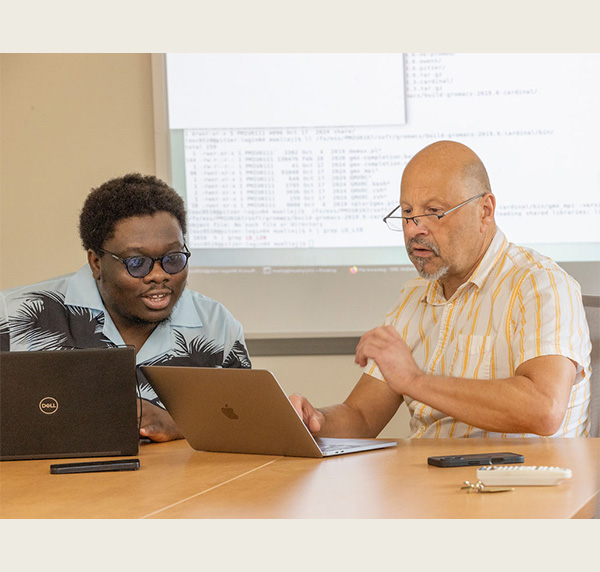 jens mueller right and Ikponwmosa Obaseki sit together at a table with laptop computers