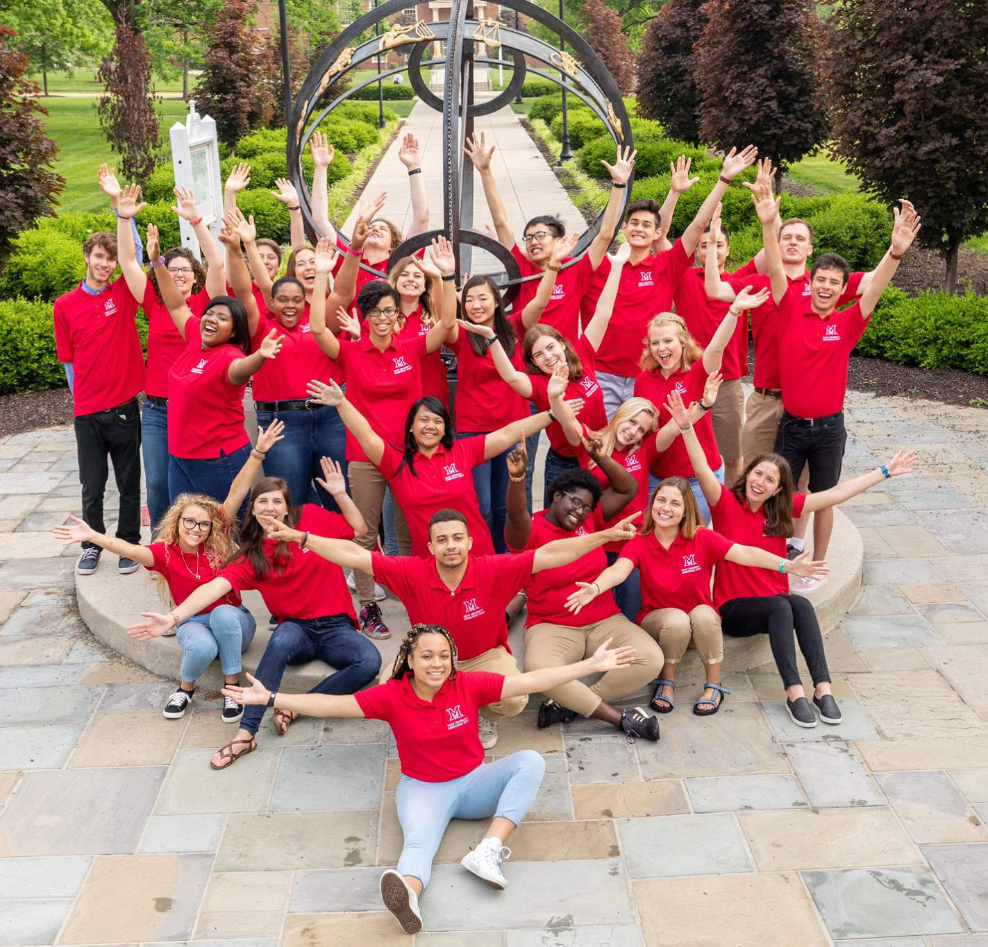 Orientation staff strike welcoming poses around the sundial