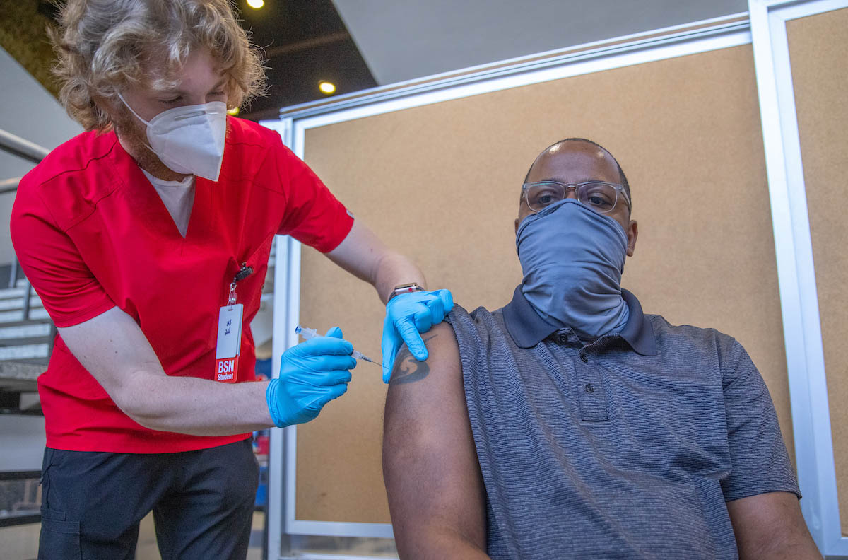 Alan McCoy receiving the shot from a Miami nursing student