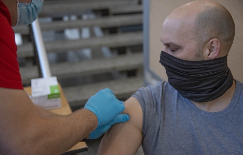 James Carsey, athletic director, getting a bandaid after the vaccine from a Miami nursing student