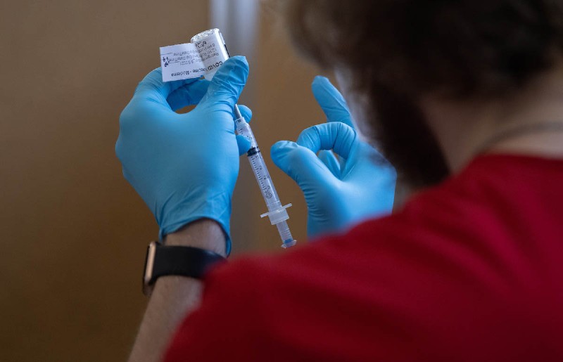 Nurse about to flick the syringe filled with the vaccine to remove air bubbles