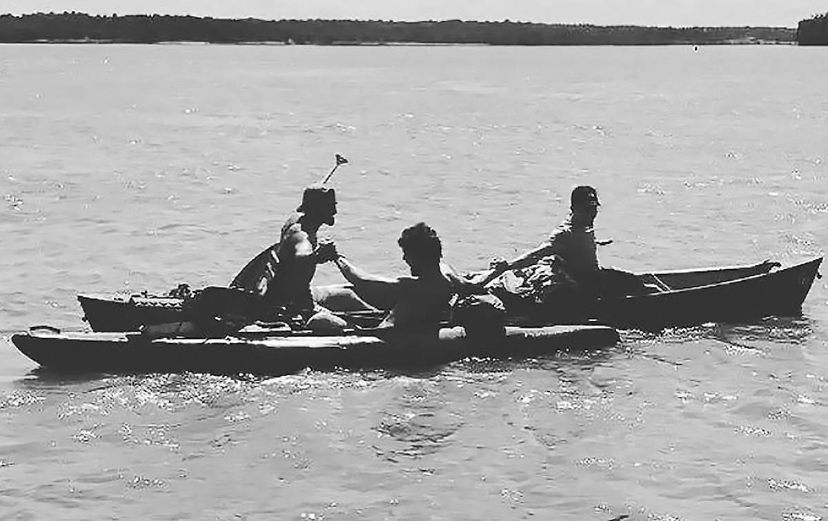 While still in the kayak and canoe, Couch, Gray, and Brezina grasp hands in triumph at the end of their journey
