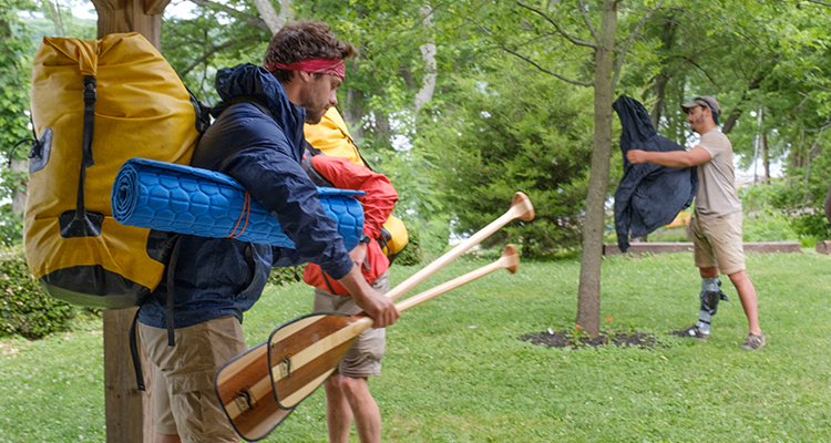 They guys carry their gear and begin setting up camp