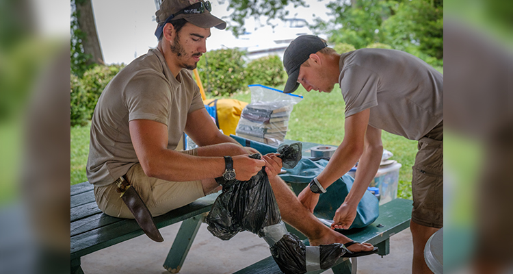 Tyler helps Jackson wrap his injured food in a garbage bag to keep it dry