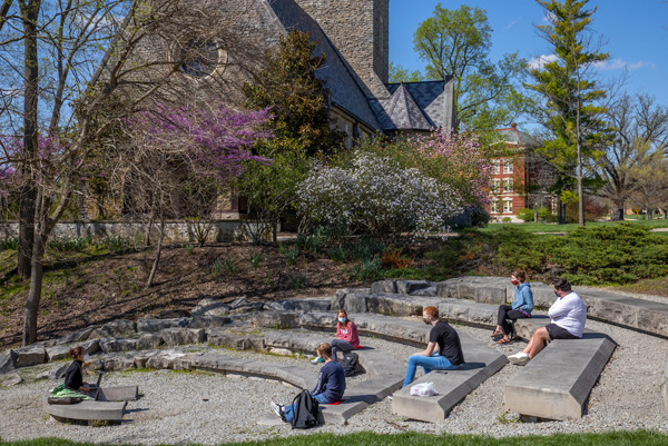 Six students sitting on the steps of the Freedom Summer Memorial with Kumler Chapel in the background.