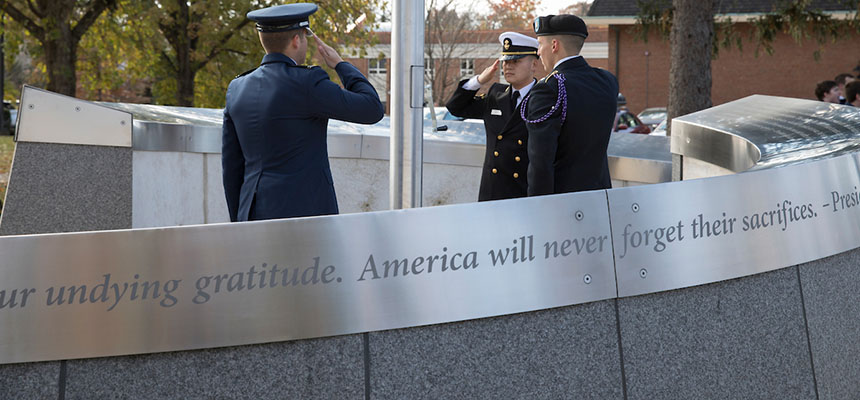 Military members salute during the dedication of the  Alumni Veterans Tribute