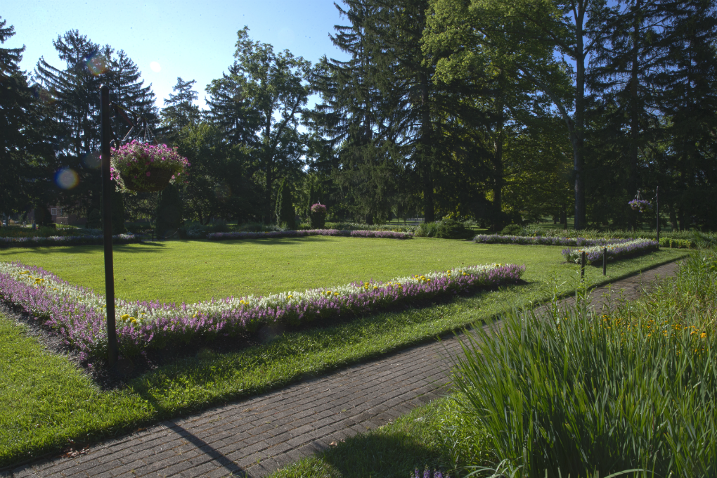  an open square lawn edged with flower beds in the center of the formal gardens