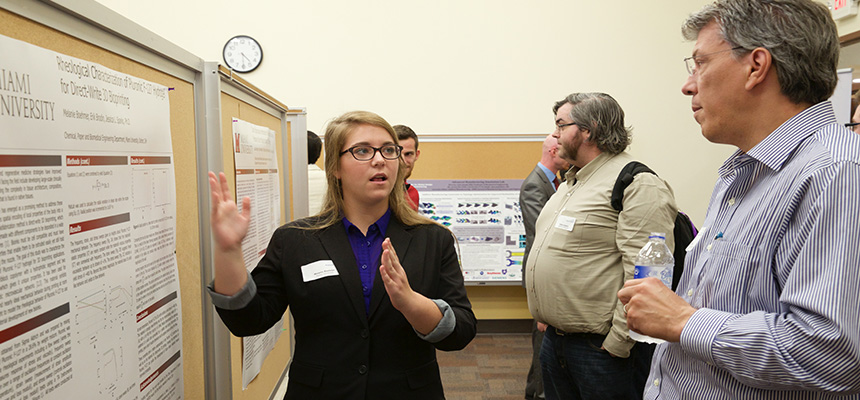  Female student presenting her poster presentation to another male student.