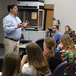 Professor Paul Harding standing in the front of the classroom talking to his students.