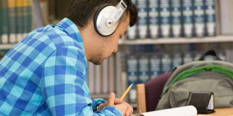  A student studying in the TRIO office with headphones on.