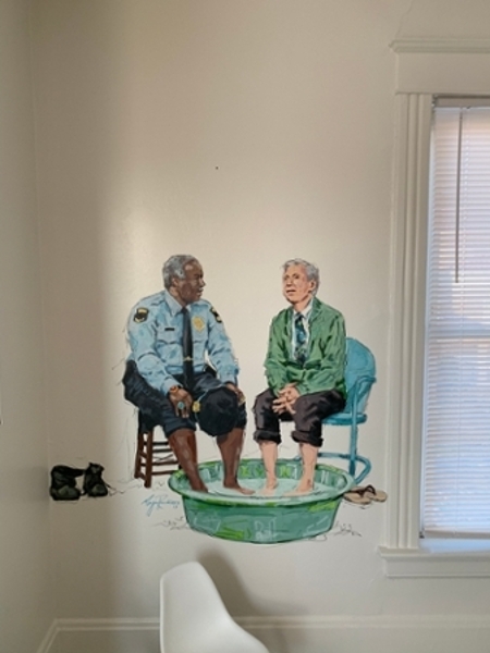 A hand painted mural of a police officer sitting with another person with their feet in a small kiddie pool.  