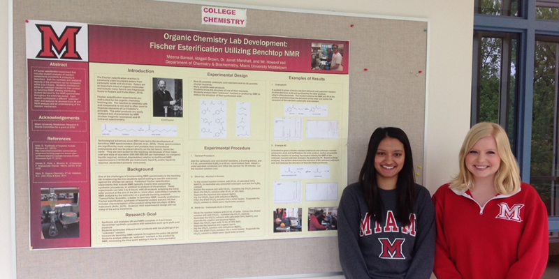  Abby and Meena stand in front of the poster they created when presenting their research project.