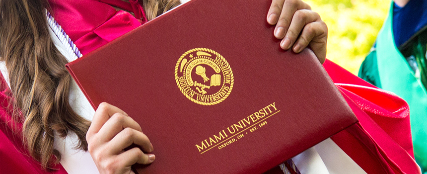 A female holding her diploma at graduation.