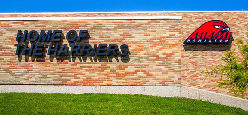 The exterior of the gymnasium with a sign that reads Home of the Harriers and the Miami Hamilton Harriers logo