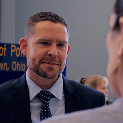 A male in a suit and tie talking to an employer during a Career Fair.