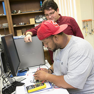 A professor helping a student work on using wires. 