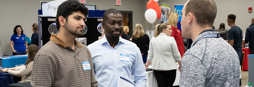 A employer talking to 2 students at the Career Fair. 
