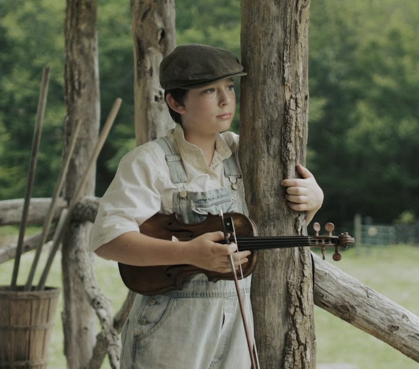 Photo of a boy holding a fiddle from the movie The Mountain Minor