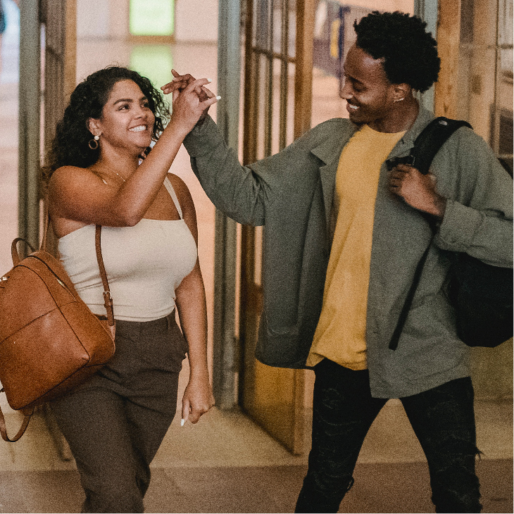 2 students walking and giving each other a high five.