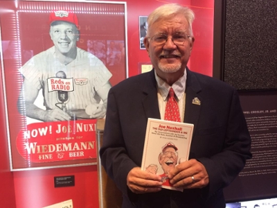 John Kiesewetter holding his book in front of a photo of Joe Nuxhall