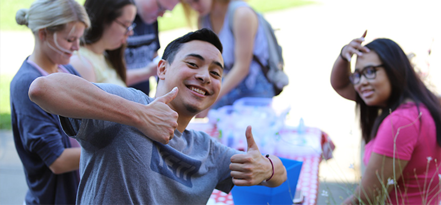 A student smiling with giving a thumbs up. 